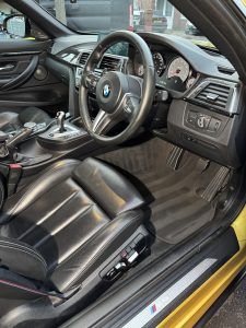 Interior of a car that has been deep cleaned, images shows steering wheel, leather drivers seat and foot well of the driver side with the dashboard in shot too
